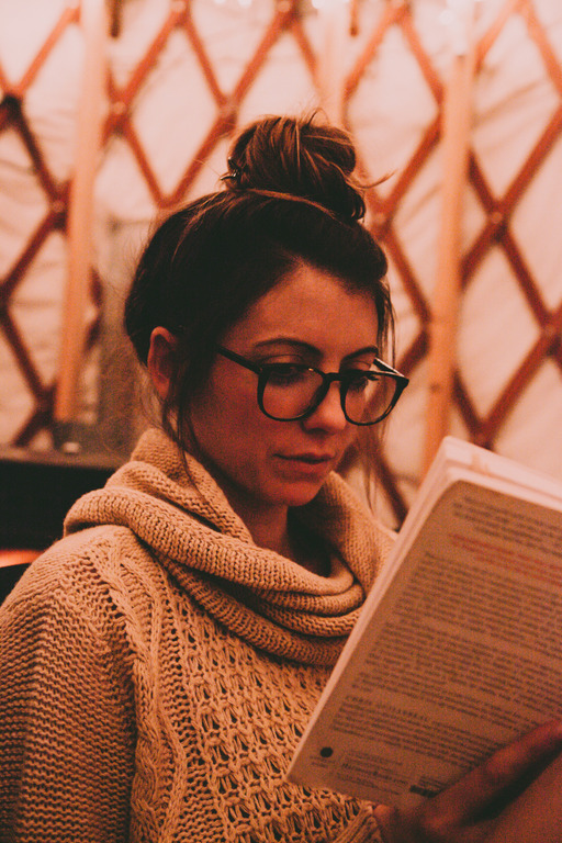 woman reading book in dim, cozy room
